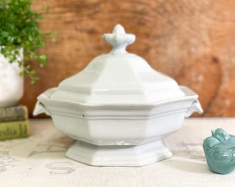 May include: White porcelain serving dish with a lid and a decorative knob. The dish has a scalloped edge and a fluted base.