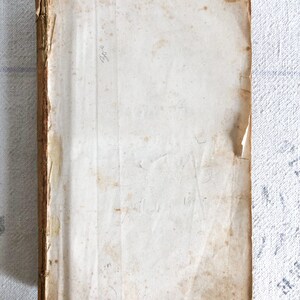 May include: A vintage book with a worn, off-white cover and a brown spine. The cover has some stains and the text "1894" is written on the top right corner.