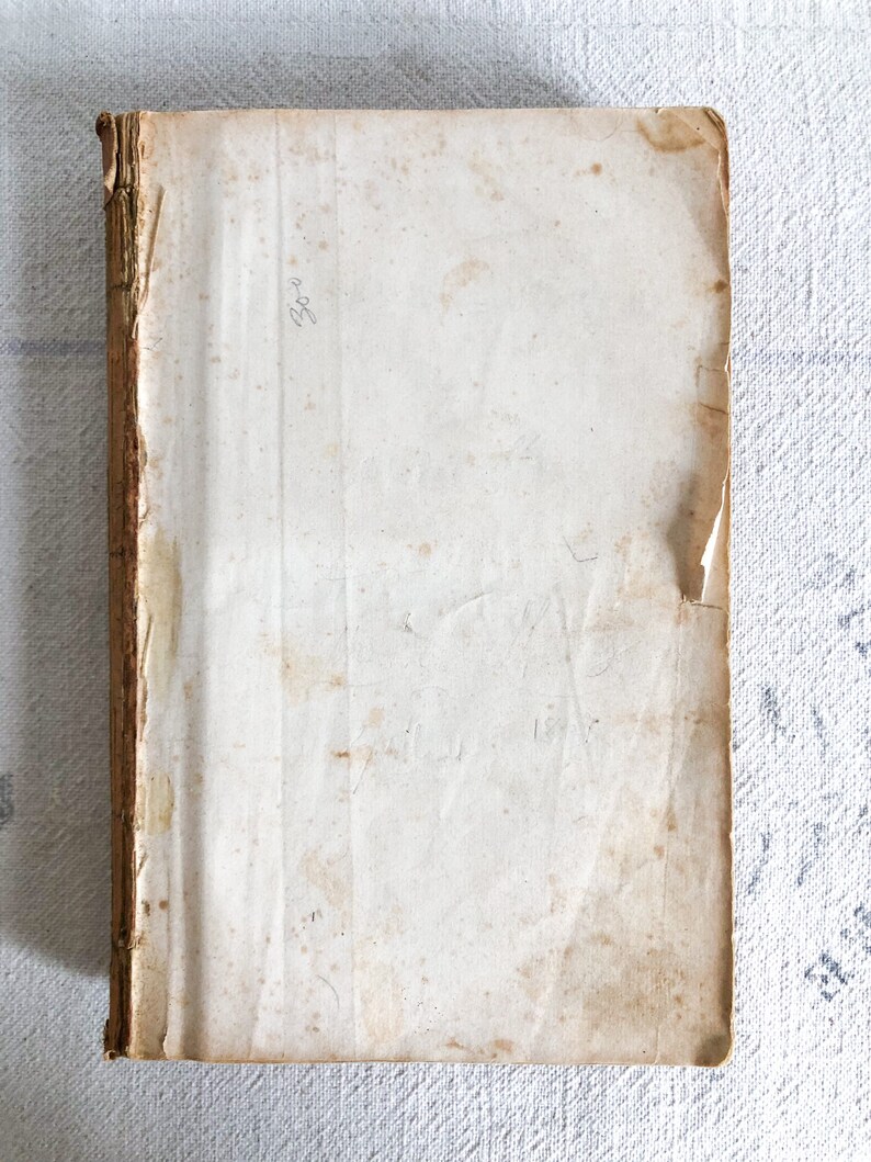 May include: A vintage book with a worn, off-white cover and a brown spine. The cover has some stains and the text "1894" is written on the top right corner.