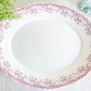 May include: A white oval serving platter with a pink floral design around the edge.