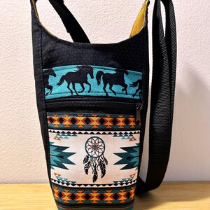 May include: A black crossbody bag with a zippered pocket and a colorful southwestern-style print featuring horses, a dreamcatcher, and geometric patterns.