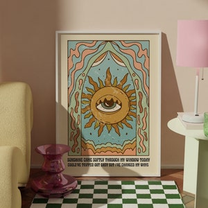 May include: A retro-style poster featuring a sun with an eye at its centre. The sun is surrounded by a colourful, abstract design. The text on the poster reads "Sunshine came softly through my window today Could've tripped out easy but I've changed my ways."