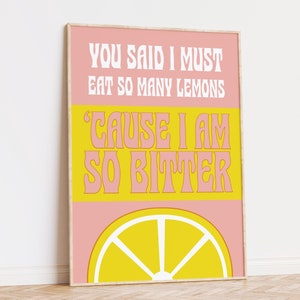 May include: A framed art print with a pink and yellow design. The print features the text "YOU SAID I MUST EAT SO MANY LEMONS 'CAUSE I AM SO BITTER" in white and pink fonts, with a yellow lemon slice at the bottom.