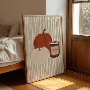 May include: Framed art print with a seasonal autumn theme. The artwork shows a large orange pumpkin, a white pumpkin, and a candle with the word "candle". The background has vertical stripes in beige and white.
