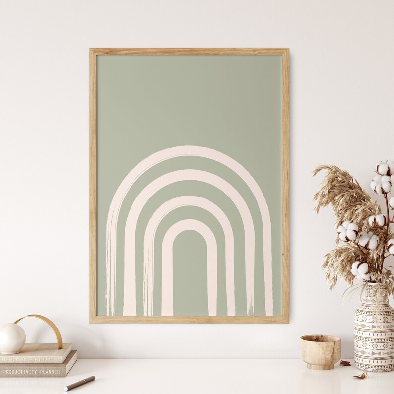 May include: A framed print with a minimalist abstract design featuring a pink and white arch shape on a sage green background.