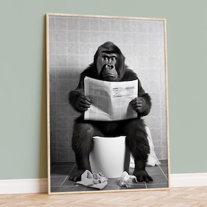 May include: A black and white photograph of a gorilla sitting on a toilet and reading a newspaper. The gorilla has a serious expression.