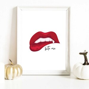 May include: A white framed print featuring a red, open mouth with fangs and the text "bite me" in black.