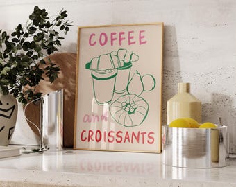 Könnte beinhalten: Ein goldfarbener gerahmter Druck mit dem Text "COFFEE and CROISSANTS" in rosa und grüner Schrift. Der Druck zeigt eine grüne Illustration von zwei Tassen Kaffee und Croissants mit Birnen und einem Gebäck.