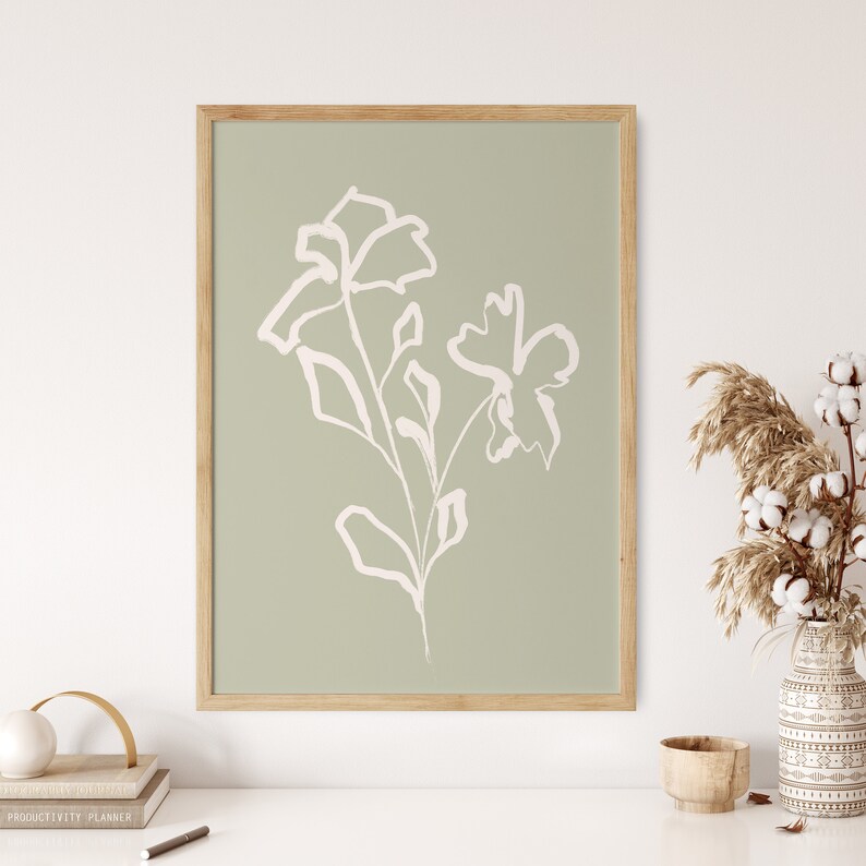 May include: A framed print with a minimalist line drawing of white flowers on a sage green background.