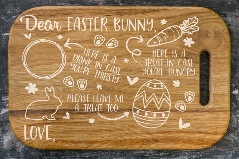 May include: Wooden cutting board with a white design of an Easter bunny, a carrot, an egg, and paw prints. The board has a handle and the text "Dear Easter Bunny, * LOVE * HERE IS A DRINK IN CASE YOU'RE THIRSTY * PLEASE LEAVE ME A TREAT TOO * HERE IS A TREAT IN CASE YOU'RE HUNGRY *" is written on it.