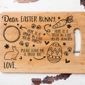 May include: A wooden cutting board with an engraved message for the Easter Bunny. It includes a circle for a drink, a carrot, an egg, and the text "Dear Easter Bunny, Here is a drink in case you're thirsty. Here is a treat in case you're hungry. Please leave me a treat too. Love,".