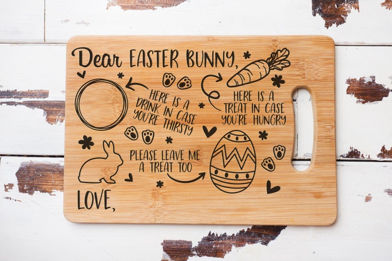 May include: A wooden cutting board with an engraved message for the Easter Bunny. It includes a circle for a drink, a carrot, an egg, and the text "Dear Easter Bunny, Here is a drink in case you're thirsty. Here is a treat in case you're hungry. Please leave me a treat too. Love,".