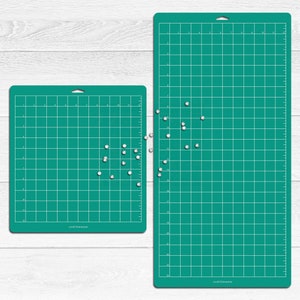 May include: Two green self-healing cutting mats with a grid pattern. The smaller mat is 12 inches by 12 inches and the larger mat is 12 inches by 24 inches. Both mats have white dots scattered on them.