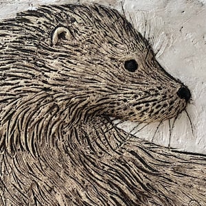 Könnte beinhalten: Nahaufnahme einer strukturierten, braunen und schwarzen Skulptur eines Otterkopfes. Die Skulptur ist so gestaltet, dass sie wie Fell aussieht.