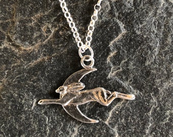 May include: Silver necklace with a pendant of a stylized hare leaping in a crescent moon shape.