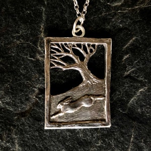 Hare running through wood pendant  necklace in silver .