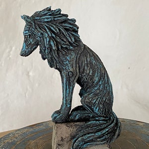 May include: A blue and grey ceramic sculpture of a wolf sitting on a base. The wolf has a textured, furry appearance and is looking to the left.