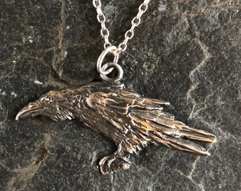 May include: A silver raven pendant necklace. The raven is detailed with textured feathers and has a silver chain.