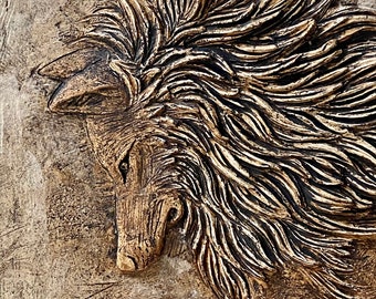 May include: A close-up of a brown and gold wolf sculpture with a textured surface. The wolf's head is tilted down and its fur is detailed with raised lines.