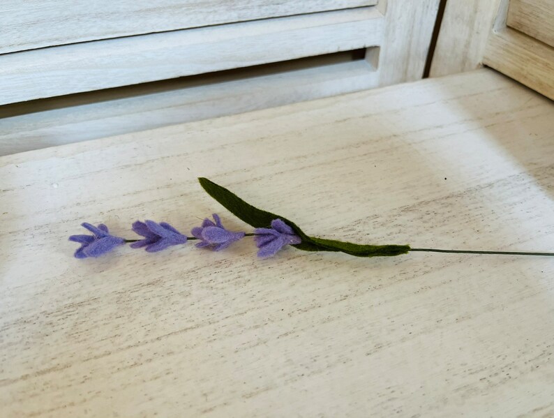 May include: A single stem of purple felt lavender with green felt leaves.
