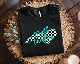 May include: Black t-shirt featuring a checkered outline of the state of North Carolina with the text "North Carolina" in turquoise.