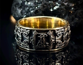 May include: A gold and black ring with an intricate design and the letter "L" in the center.