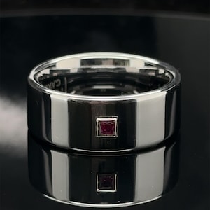 May include: A silver band with a small, square, ruby-red gemstone set in the center.