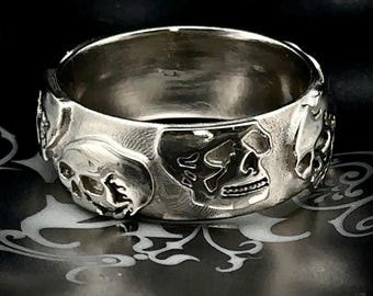 May include: A silver ring with a skull design. The ring is made of metal and has a polished finish.