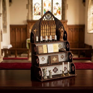 Könnte beinhalten: Ein dunkelbraunes Holzregal mit gotischem Bogen-Design. Das Regal hat drei Ebenen und hält Kerzen, Bücher und religiöse Figuren. Der Hintergrund zeigt einen Kircheninnenraum mit Buntglasfenstern.