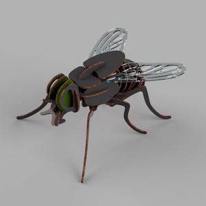 Puede incluir: Un modelo de mosca de madera pintado en negro y verde con alas translúcidas y detalladas. La mosca está posada sobre sus patas.