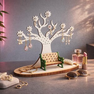May include: A white wooden jewelry organiser in the shape of a tree, adorned with flower-shaped details, displaying various earrings. A small bench and wooden base are in front of the tree. Other jewellery, sunglasses, perfume, and lipstick are also displayed.