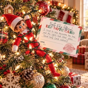 May include: A plush elf doll in a red suit and hat tangled in green Christmas tree light strings next to a rectangular note card that reads North Pole Official Elf Note Card, I tried to help decorate the tree and the lights had other plans. Send help (and cookies)!, Love, Tosel, with a Santa Claus postmark.