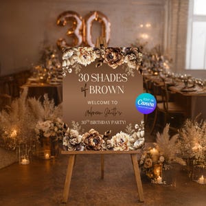 Puede incluir: Un letrero de bienvenida rectangular marr&oacute;n sobre un caballete de madera con ilustraciones florales en la parte superior e inferior. El texto dice 30 SHADES of BROWN WELCOME TO Aubreon Smith's 30TH BIRTHDAY PARTY! Un logo azul de Canva es visible.