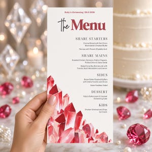 May include: A vertical rectangular menu card for Ruby's Christening on 29.11.2026. The white card features a watercolour illustration of red crystals at the bottom and black text listing food items under headings: Share Starters, Share Mains, Sides, Dessert, and Kids.