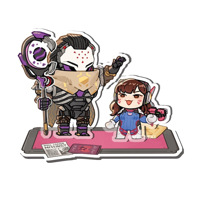 May include: A sticker featuring two cartoon characters from the video game Overwatch. One character is a robot with a staff, and the other is a girl holding a gun. The sticker is on a pink mat with a newspaper that reads "Null Leader Missing?"