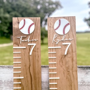 May include: Two wooden growth charts with baseball graphics and white numbers. The charts are labeled "Tucker 7" and "Ryder 7".