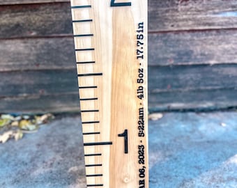 May include: A wooden growth chart with black markings and numbers. The chart is marked with the date "MAR 06, 2023 - 5:22am - 4lb 5oz - 17.75in".
