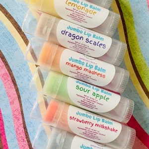 May include: A set of ten colorful lip balms in clear tubes with white labels. Each label has the text "Jumbo Lip Balm" and a different flavor name, such as "bubblegum", "lemonade", "dragon scales", "mango madness", "sour apple", "strawberry milkshake", "blue raspberry", and "banana monkey farts".