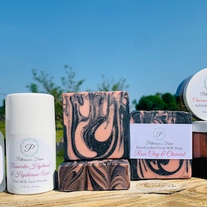 May include: A set of skincare products featuring rose clay and charcoal. The set includes a face serum, face cream, soap, and a facial scrub. The products are packaged in white containers with black and pink labels.