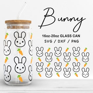 Pode incluir: Uma lata de vidro transparente com tampa de madeira e canudo de vidro. A lata é decorada com um padrão repetido de rostos de coelhos brancos e cenouras laranja. O texto na imagem diz "Bunny" e "16oz-20oz GLASS CAN".