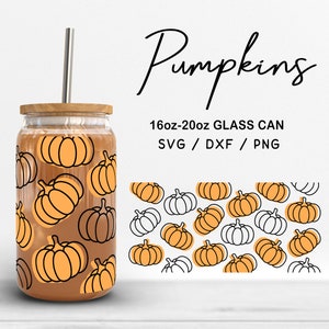Puede incluir: Una lata de vidrio con tapa de madera y pajita plateada, con un patrón repetido de calabazas naranjas con contornos negros. El texto "Pumpkins" está escrito en cursiva, y la lata está etiquetada como "16oz-20oz GLASS CAN".
