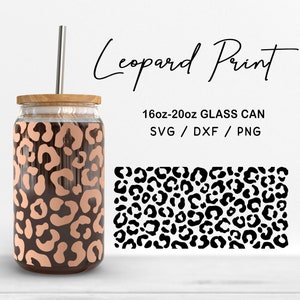 Puede incluir: Una lata de vidrio con tapa de bambú y pajita de acero inoxidable. La lata presenta un diseño de estampado de leopardo en tonos marrón y beige. También se ve el texto "Leopard Print" y "16oz-20oz GLASS CAN".