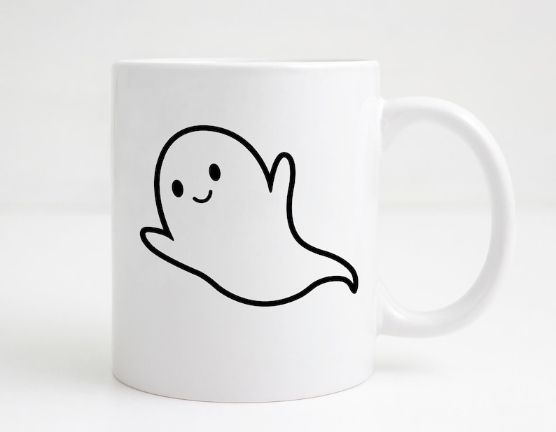 May include: White ceramic mug with a black and white cartoon ghost illustration. The ghost has a smiling face and a raised arm. The mug has a curved handle and is suitable for hot or cold drinks.