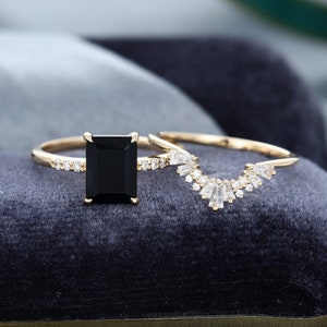 May include: A black emerald cut gemstone engagement ring with a pave diamond band and a matching diamond accented contoured wedding band.