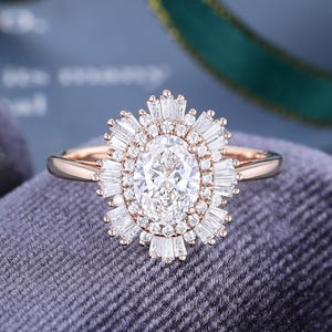 May include: A rose gold ring featuring a central oval-cut stone surrounded by a halo of small round stones and an outer sunburst arrangement of baguette-cut stones. The band is smooth and polished, showcasing a detailed, multi-layered design.