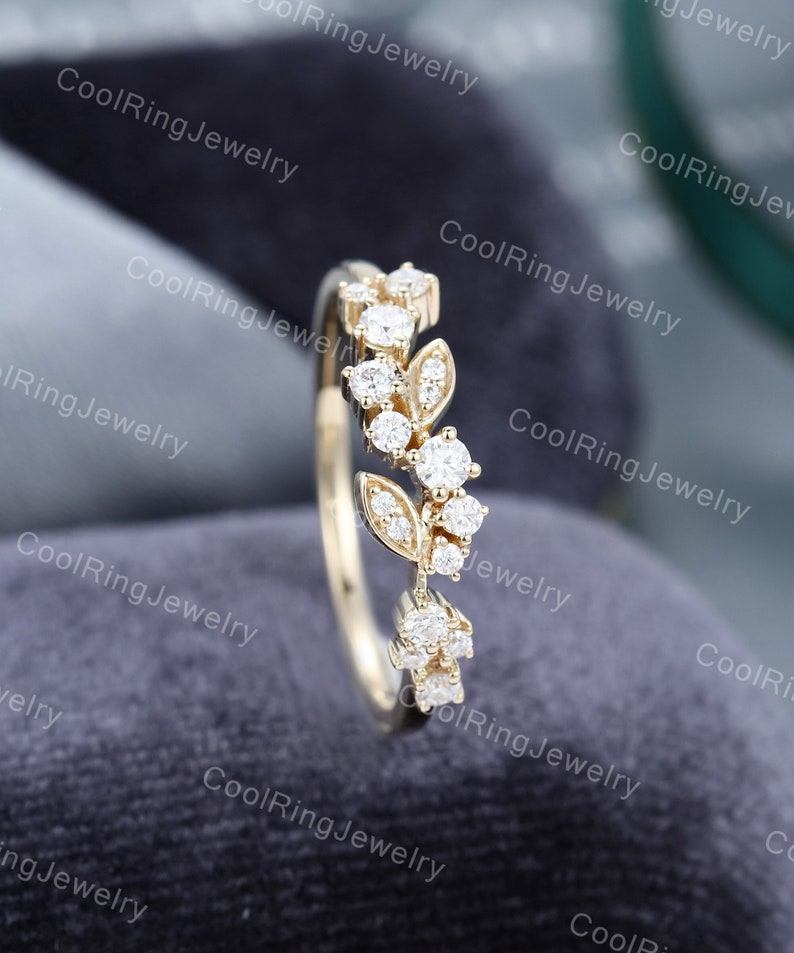 Op de afbeelding: Een delicate gouden ring met een bloemmotief met kleine, glinsterende diamanten. De ring ligt op een grijze achtergrond.