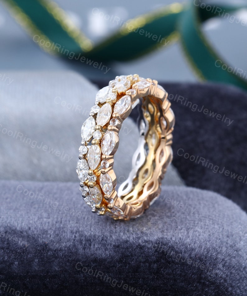 May include: A gold wedding band with a double row of marquise-shaped diamonds. The diamonds are set in a pave setting and are surrounded by smaller round diamonds.