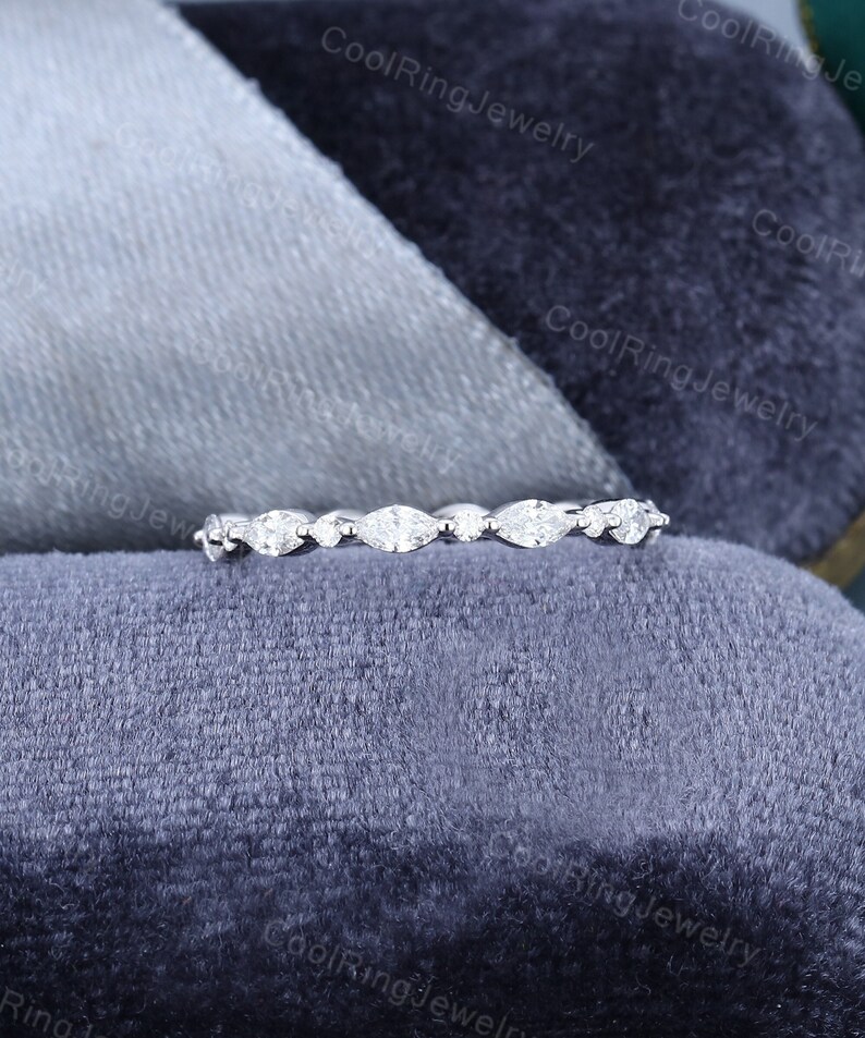 May include: A delicate silver band with a row of marquise-shaped diamonds set in a pave setting.