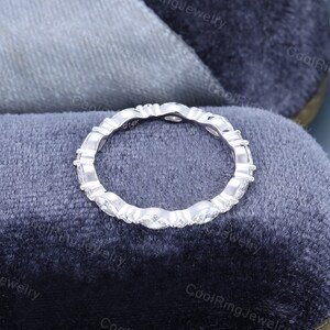 May include: A silver band ring with a row of small, oval-shaped diamonds set in a pave setting. The ring is marked "914K" on the inside.
