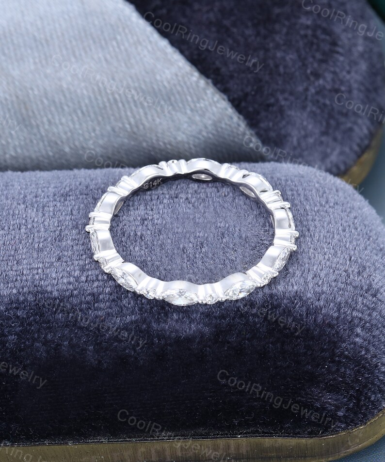 May include: A silver band ring with a row of small, oval-shaped diamonds set in a pave setting. The ring is marked "914K" on the inside.